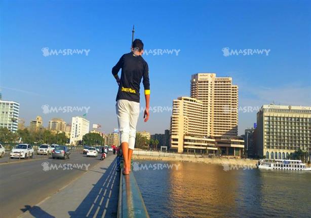 شاب يمشي على سور كوبري قصر النيل