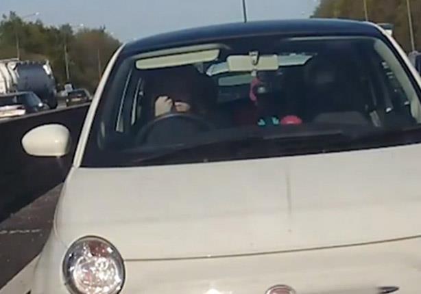 سيدة تقوم بوضع مساحيق التجميل أثناء القيادة