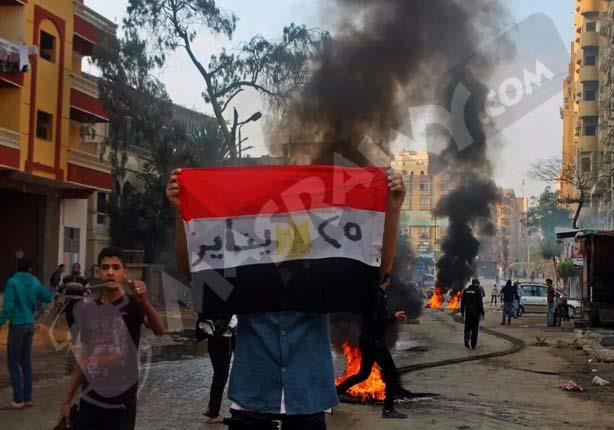 صورة لأحد المتظاهرين يرفع علم مصر في إحيء ذكري 25 يناير بالهرم