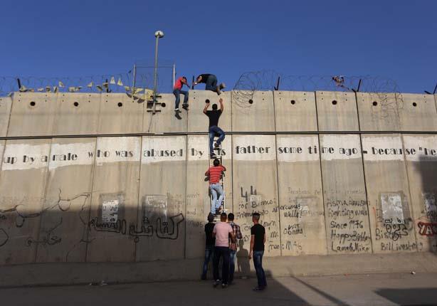 فلسطينيون يتسلقون الجدار العازل شمال القدس ليتمكنوا من صلاة أول جمعة في رمضان بالمسجد الأقصى